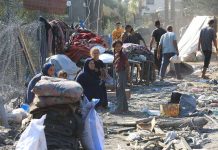 People in makeshift camp with tents and belongings.