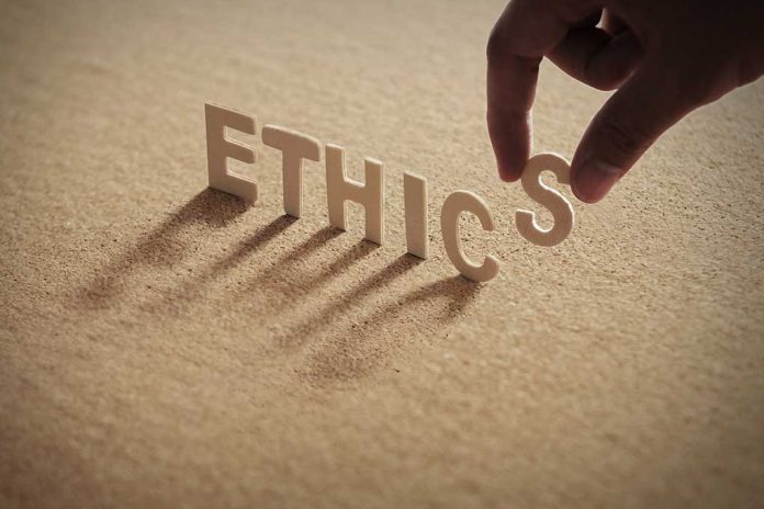 Hand placing the letter "S" in the word "ETHICS".