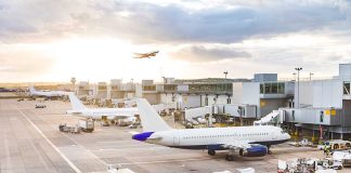 Airport with airplanes, runway, and terminal at sunset.