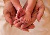 Adult hands holding newborn baby feet