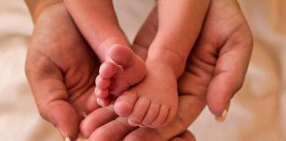 Adult hands holding newborn baby feet