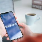 Person holding phone with Facebook app open