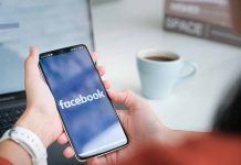 Person holding phone with Facebook app open