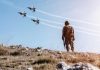 Soldier watching jets flying in blue sky
