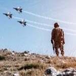 Soldier watching jets flying in blue sky