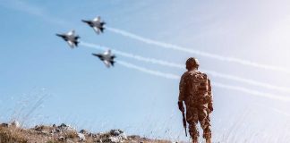 Soldier watching jets flying in blue sky