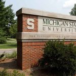Michigan State University entrance sign with bushes and trees.