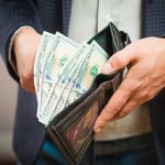 Person holding wallet with cash inside