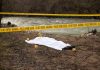 Crime scene by river with covered body and markers