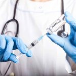 Doctor filling syringe with vaccine from vial