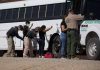 Border patrol officers investigating people near a bus