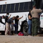 Border patrol officers investigating people near a bus