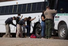 Border patrol officers investigating people near a bus