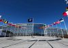 Flags outside NATO headquarters building under clear blue sky