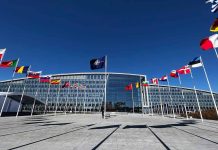 Flags outside NATO headquarters building under clear blue sky