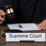 Judge with gavel and Supreme Court nameplate