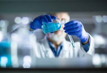 Scientist pouring blue liquid into test tube.