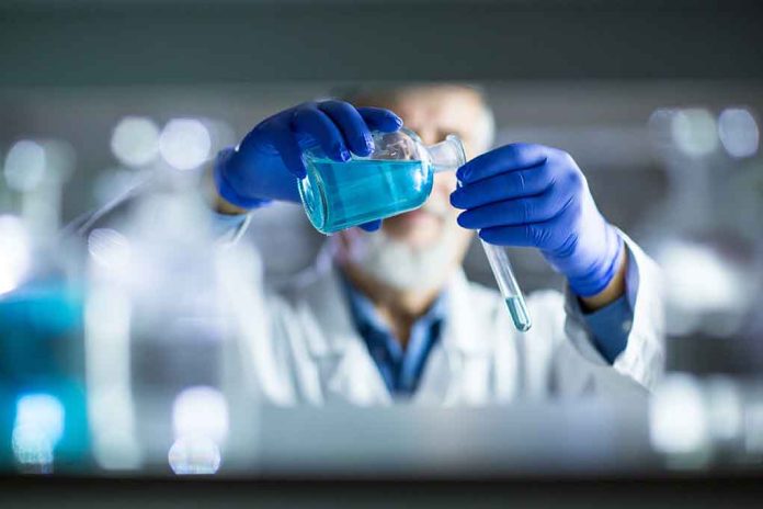 Scientist pouring blue liquid into test tube.
