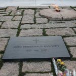 Gravestone with eternal flame and flowers nearby