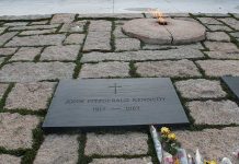 Gravestone with eternal flame and flowers nearby