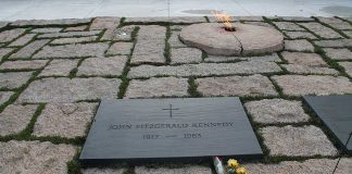 Gravestone with eternal flame and flowers nearby