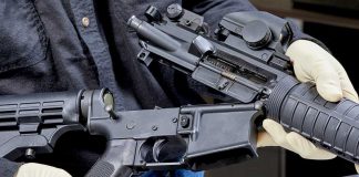Person assembling a black rifle with gloves on