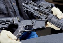 Person assembling a black rifle with gloves on