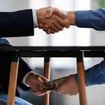 Handshake with money exchanged under table
