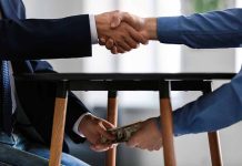 Handshake with money exchanged under table