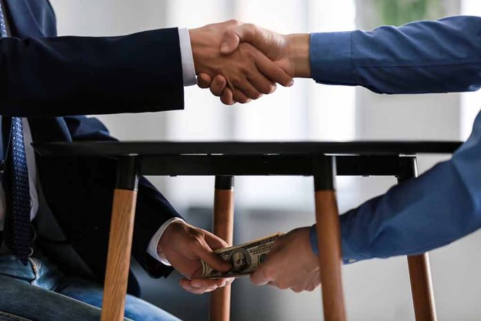 1225177960 featured image Handshake with money exchanged under table