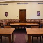 Empty courtroom with wooden tables chairs and a door