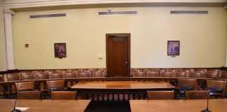 Empty courtroom with wooden tables chairs and a door