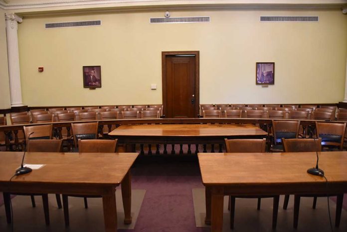 1291095706 featured image Empty courtroom with wooden tables chairs and a door