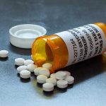 Prescription bottle with pills spilled on table