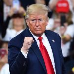 Man in suit making a fist gesture at rally