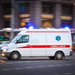 Ambulance driving on urban street with lights flashing