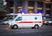 Ambulance driving on urban street with lights flashing