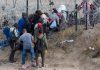 People near barbed wire fence in outdoor area