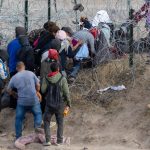 People near barbed wire fence in outdoor area
