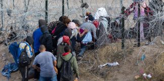 People near barbed wire fence in outdoor area