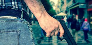Person holding a gun in a crowded street