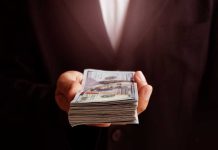 Hand holding a stack of hundred dollar bills