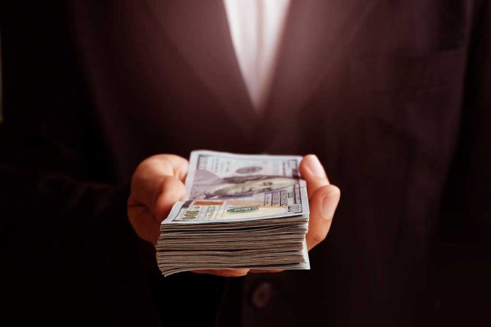 71912373 featured image Hand holding a stack of hundred dollar bills
