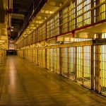Empty hallway between rows of prison cells