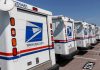 Row of USPS mail trucks parked in lot