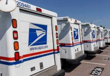 Row of USPS mail trucks parked in lot