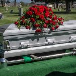 Silver casket with red roses in a cemetery