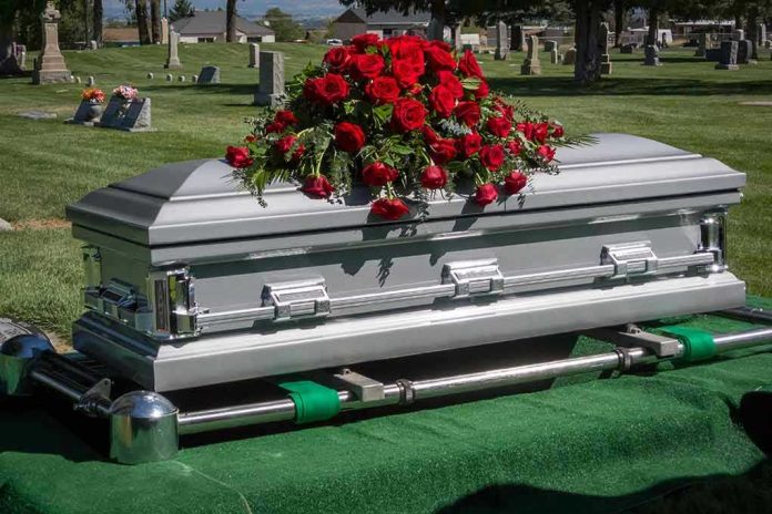 175194851 Silver casket with red roses in a cemetery