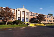 Exterior view of a brick school building with yellow steps and a cross on top