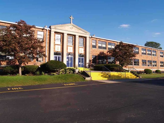 shutterstock_18910786.jpg Exterior view of a brick school building with yellow steps and a cross on top